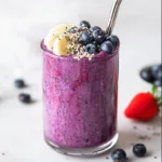 Berry protein smoothie with banana, blueberries, and chia seeds in glass