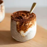Protein tiramisu chia pudding with cocoa top and spoon swipe