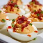 Creamy spicy deviled eggs with turkey bacon and sriracha drizzle