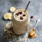 Mason jar peanut butter oat smoothie with oats and cranberries on top