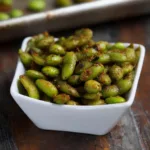 Close-up of crispy roasted edamame in a white bowl, vegan protein snack