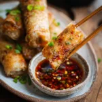 Crispy rice paper roll dipped in soy chili sauce with chopsticks