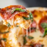 2-Ingredient Cottage Cheese Pizza Bowl (High-Protein, 5-Minute Lunch!) 10 spoon lifting cheesy bite of cottage cheese pizza bowl with basil and pepperoni