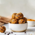 Pumpkin protein balls stacked in a white bowl on marble surface