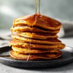 stack of fluffy high protein pumpkin pancakes with maple syrup