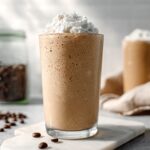 Creamy coffee protein shake topped with whipped cream on marble counter