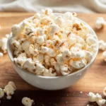 2-Ingredient Protein Popcorn (Crispy, Easy, and High-Protein!) 7 Bowl of protein popcorn with vanilla dust on wooden board