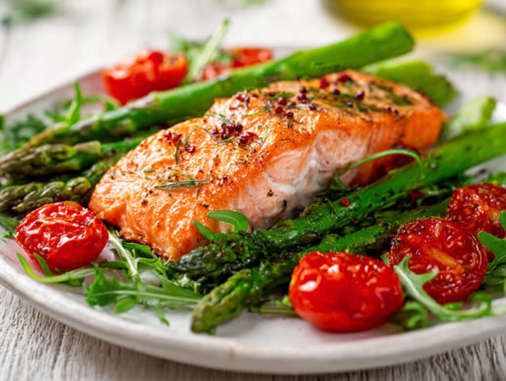 baked salmon with asparagus and cherry tomatoes on a white plate