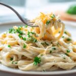 creamy cauliflower alfredo pasta twirled on a fork with parsley garnish
