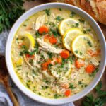 creamy chicken lemon orzo soup with parsley, carrots, and lemon slices in a bowl