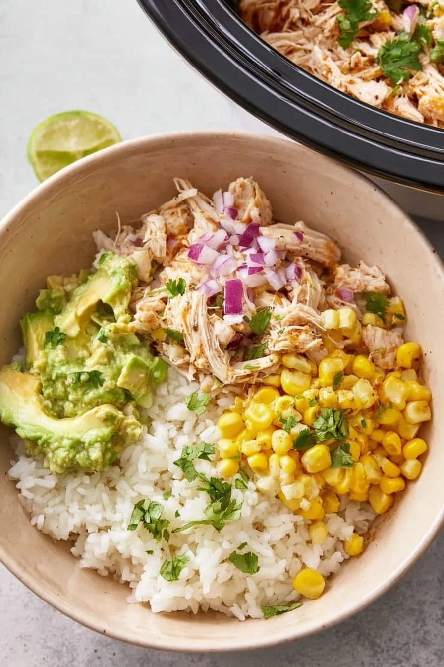 Shredded slow cooker cilantro lime chicken served in a bowl with garnishes